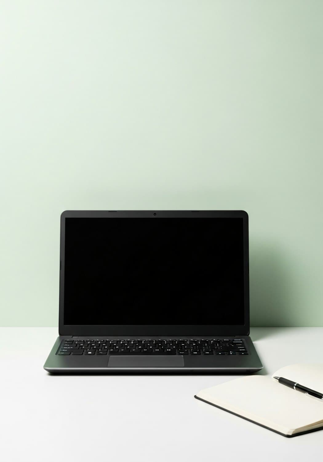 Aufgeräumter Arbeitsplatz mit Laptop, Notizbuch und Stift